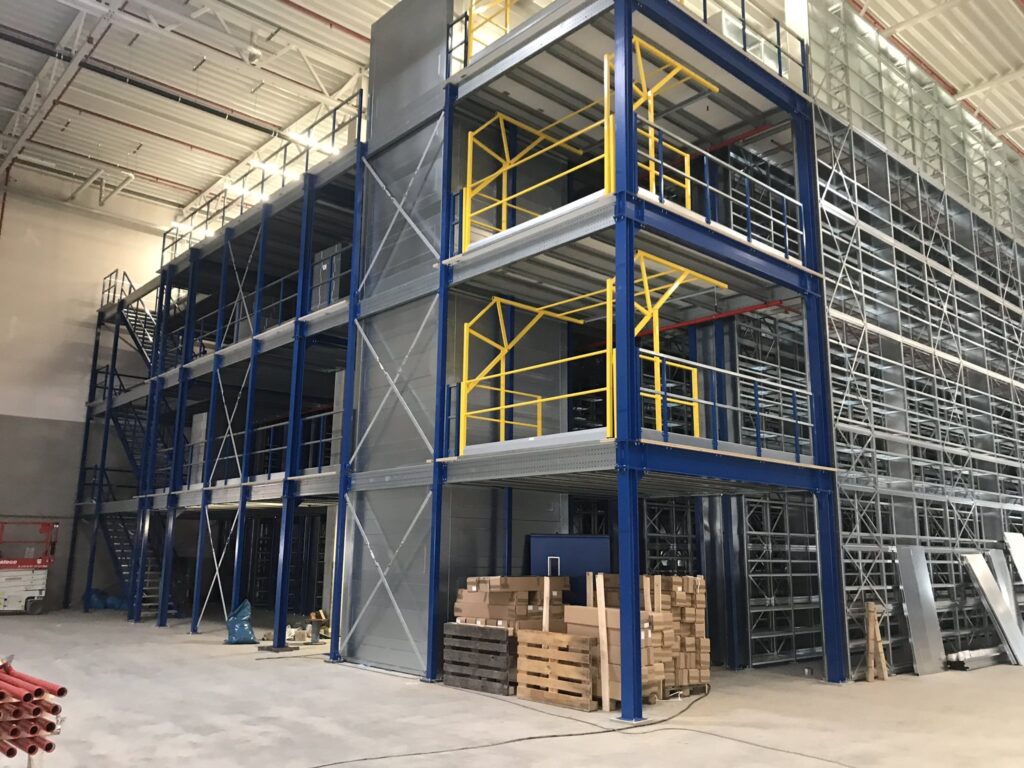 Mezzanine vloer op maat met stalen constructie, trap en gele leuningen in magazijn