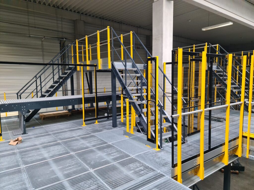 Mezzanine vloer op maat met stalen constructie, trap en gele leuningen in magazijn