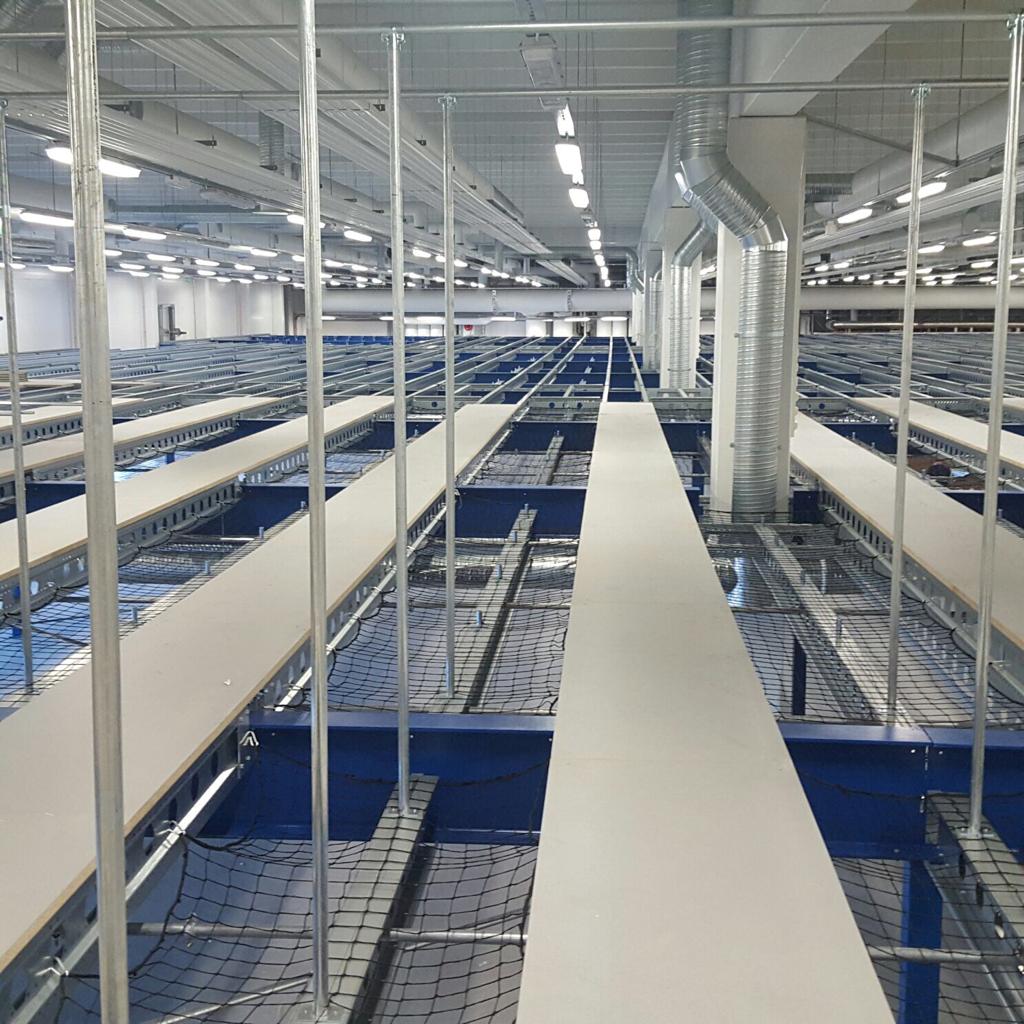 Mezzanine vloer op maat met stalen constructie, lange loopbruggen en veiligheidsnetten voor magazijn