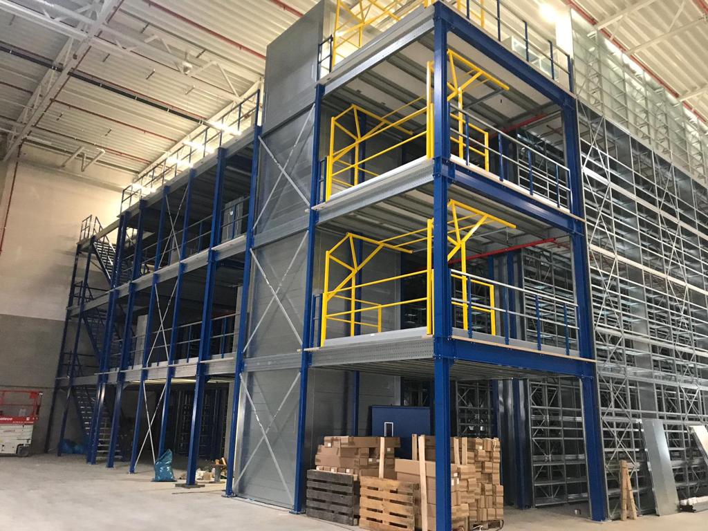 Mezzanine vloer op maat met stalen constructie, gele leuning, trap en vloerplaten in magazijn