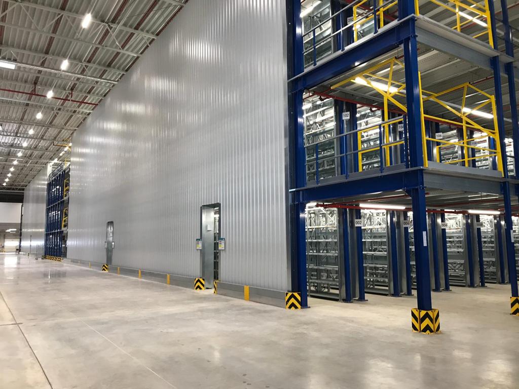 Mezzanine vloer op maat met stalen constructie en gele leuningen boven opslagrekken in magazijn