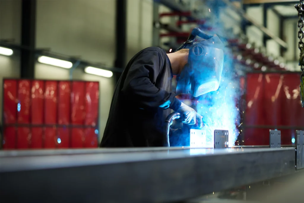 Entresolvloer op maat in bedrijfshal, lasser monteert stalen constructie en lasnaden