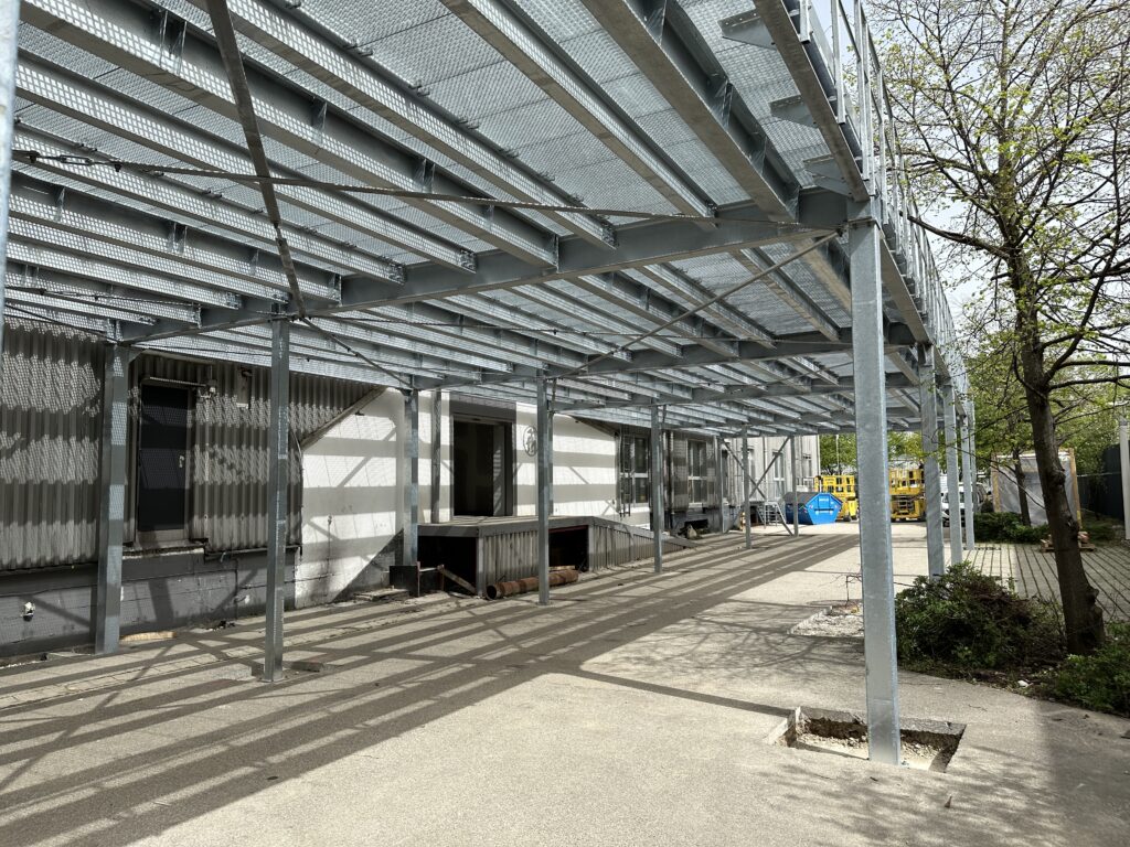 a metal structure with a building in the background