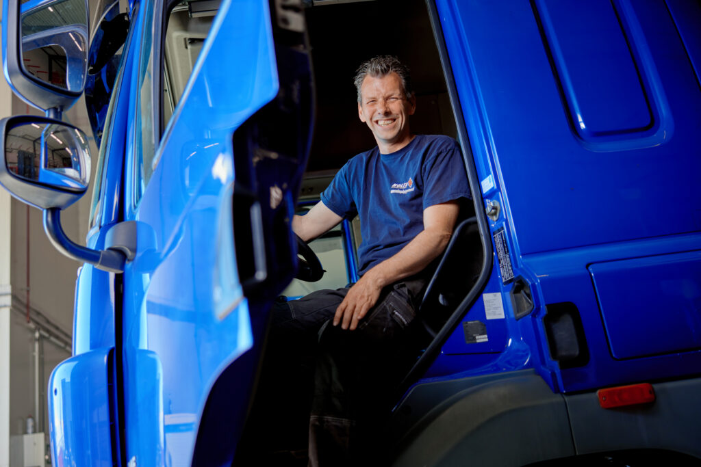a man sitting in the driver's seat of a blue truck