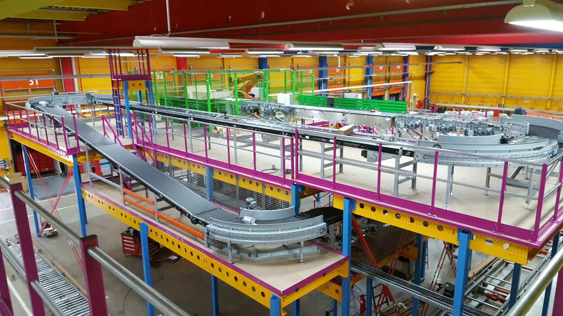 Mezzanine vloer op maat met stalen constructie, leuning en transportband in magazijn