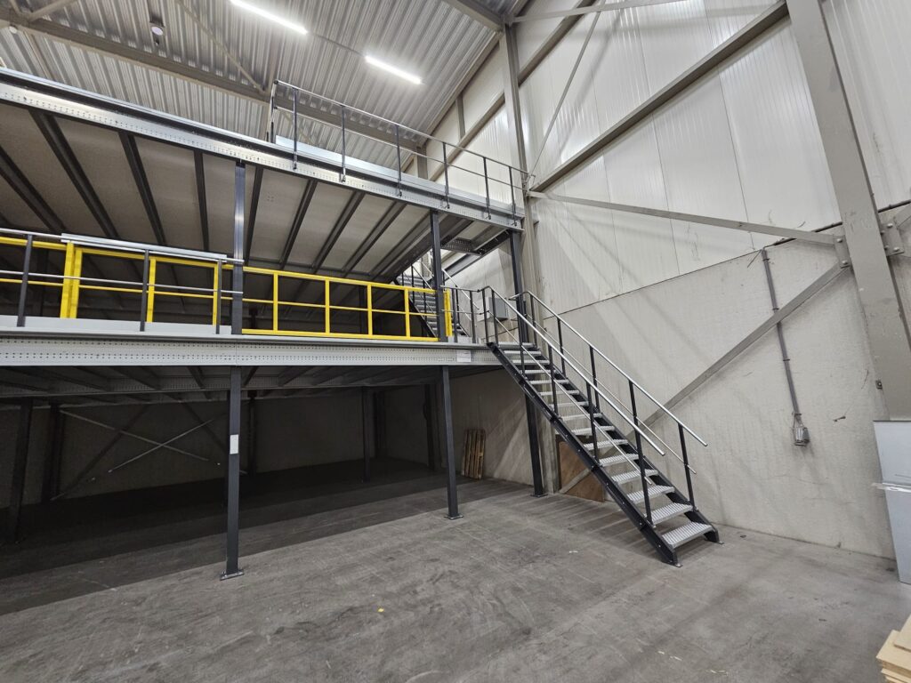 Mezzanine vloer op maat met stalen constructie, trap en gele leuning in bedrijfshal