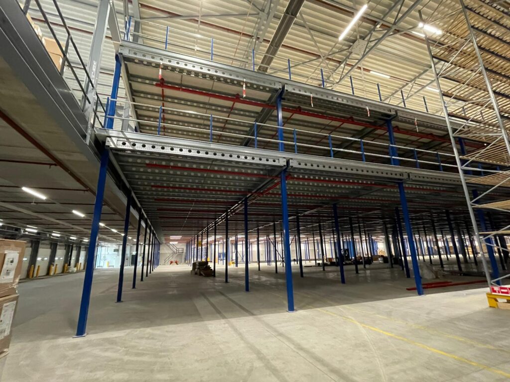 Entresolvloer stalen constructie met blauwe kolommen en relingen op maat voor magazijn