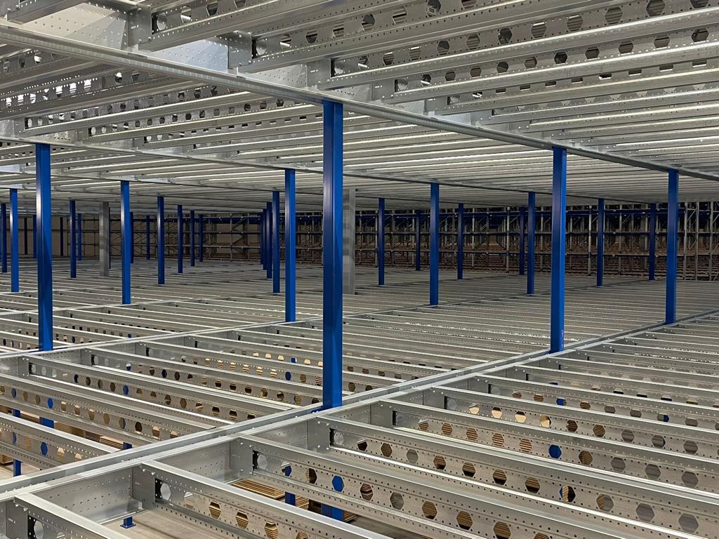 Mezzanine vloer op maat met stalen constructie, draagliggers en blauwe kolommen in magazijn