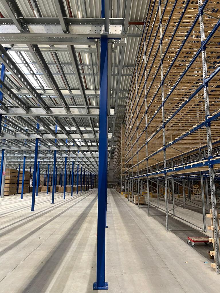 Entresolvloer op maat met stalen constructie en kolommen naast palletstellingen in magazijn