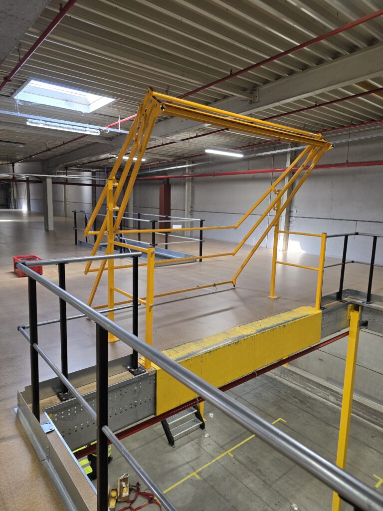Mezzanine vloer met gele klaphek stalen constructie trap en leuning op maat voor magazijn
