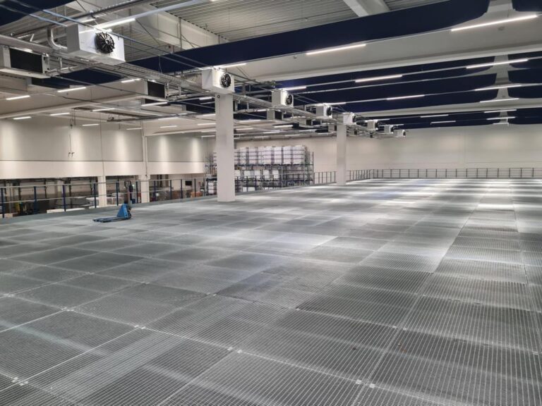 Mezzanine vloer op maat met stalen roostervloer en leuning in grote bedrijfshal