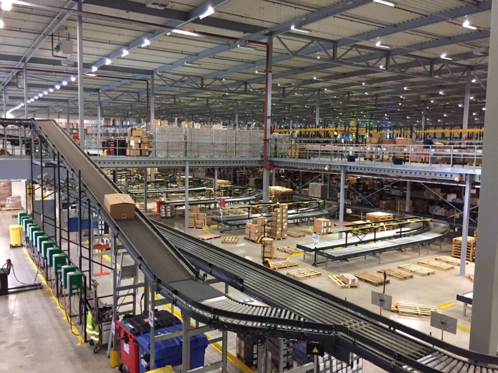 Mezzanine vloer op maat met stalen constructie, transportbanden en trap in magazijn