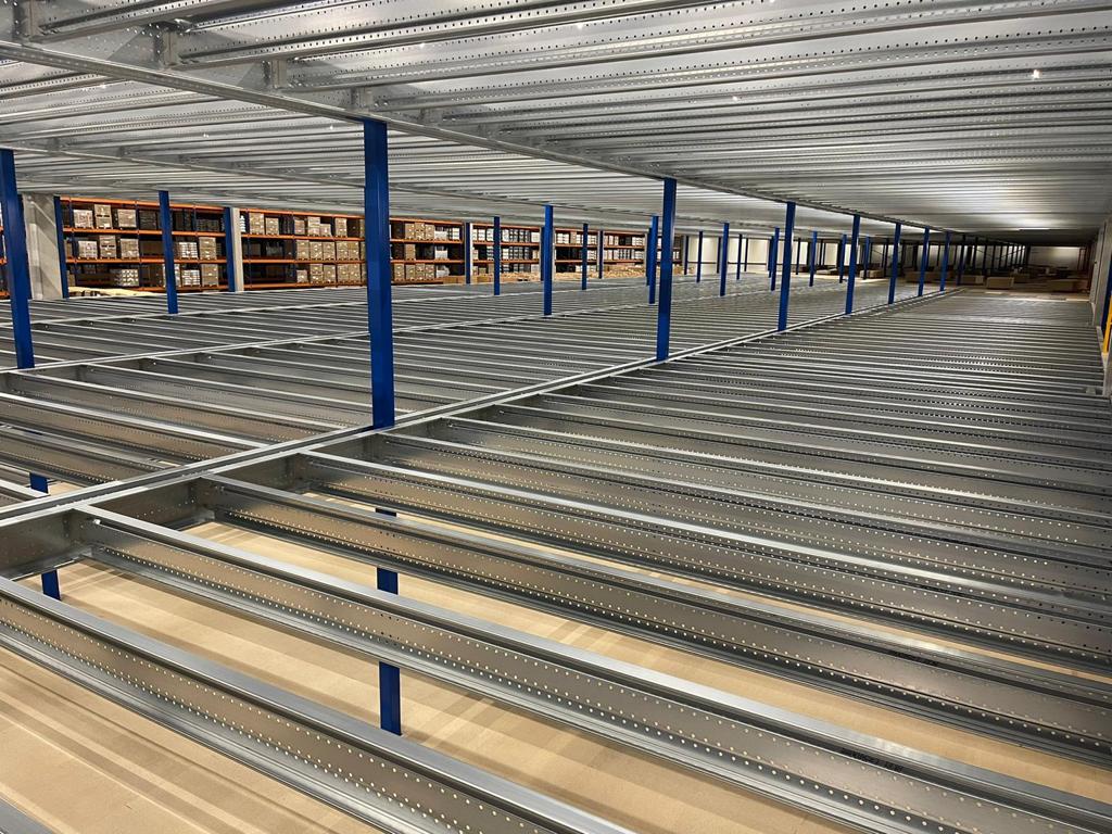Mezzanine vloer op maat met stalen draagbalken en blauwe kolommen in magazijn