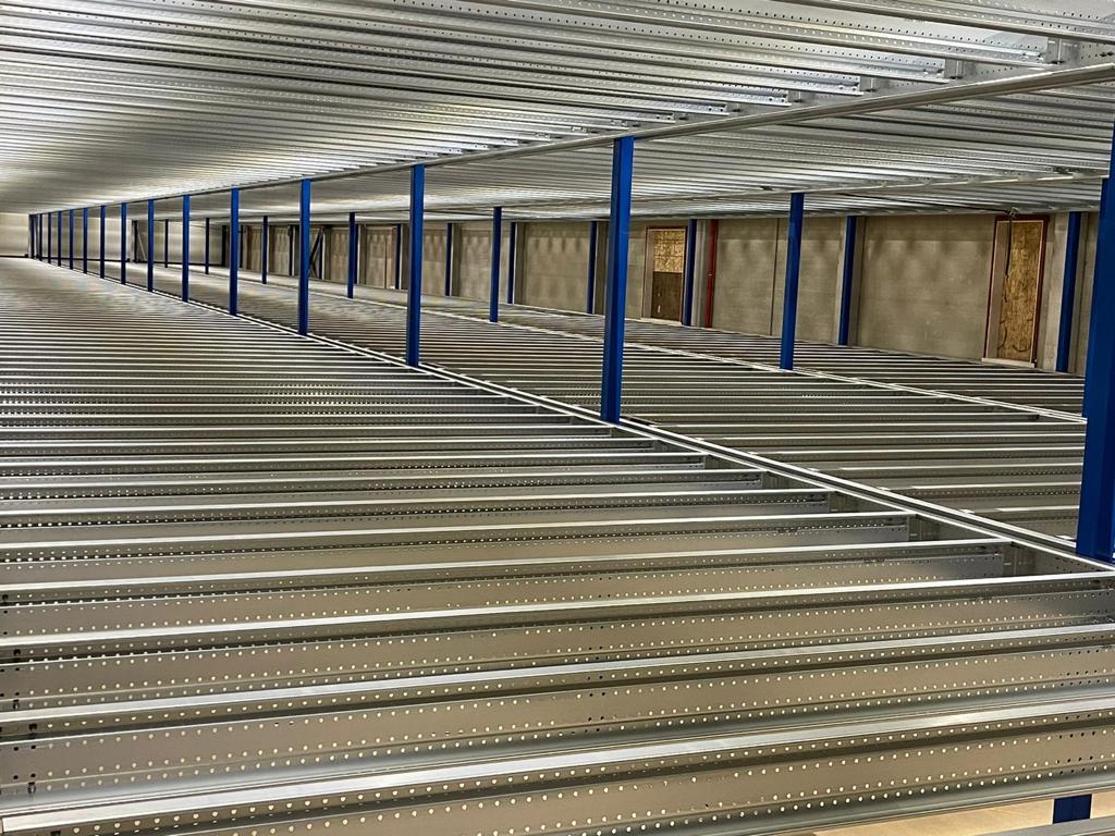 Entresolvloer op maat met stalen constructie, blauwe kolommen en draagbalken in loods