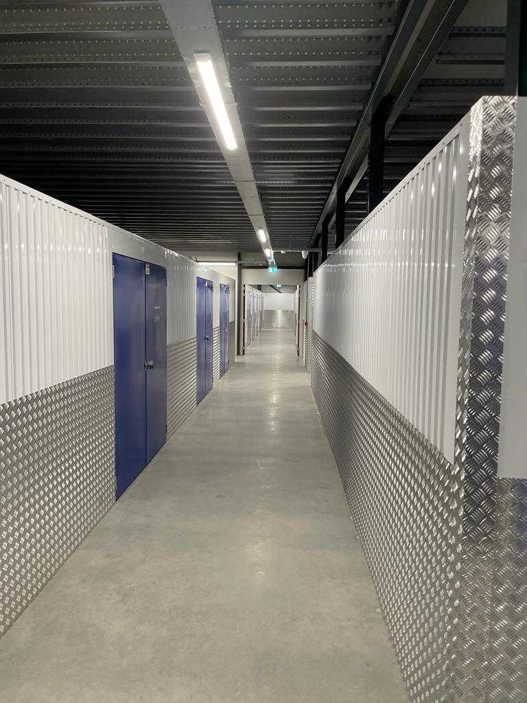 Mezzanine vloer op maat in bedrijfsruimte, zicht op gang met stalen constructie, betonvloer en blauwe deuren