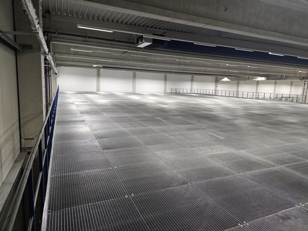 Entresolvloer op maat met stalen roostervloer en leuning in ruime magazijn